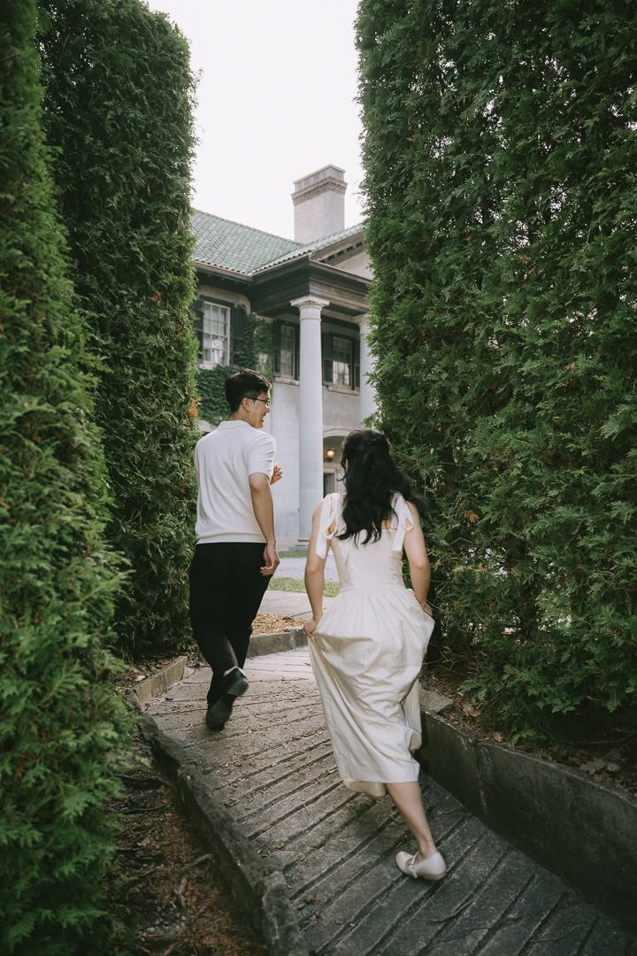 Couple framed by tall evergreens at Parkwood Estate exterior, Oshawa