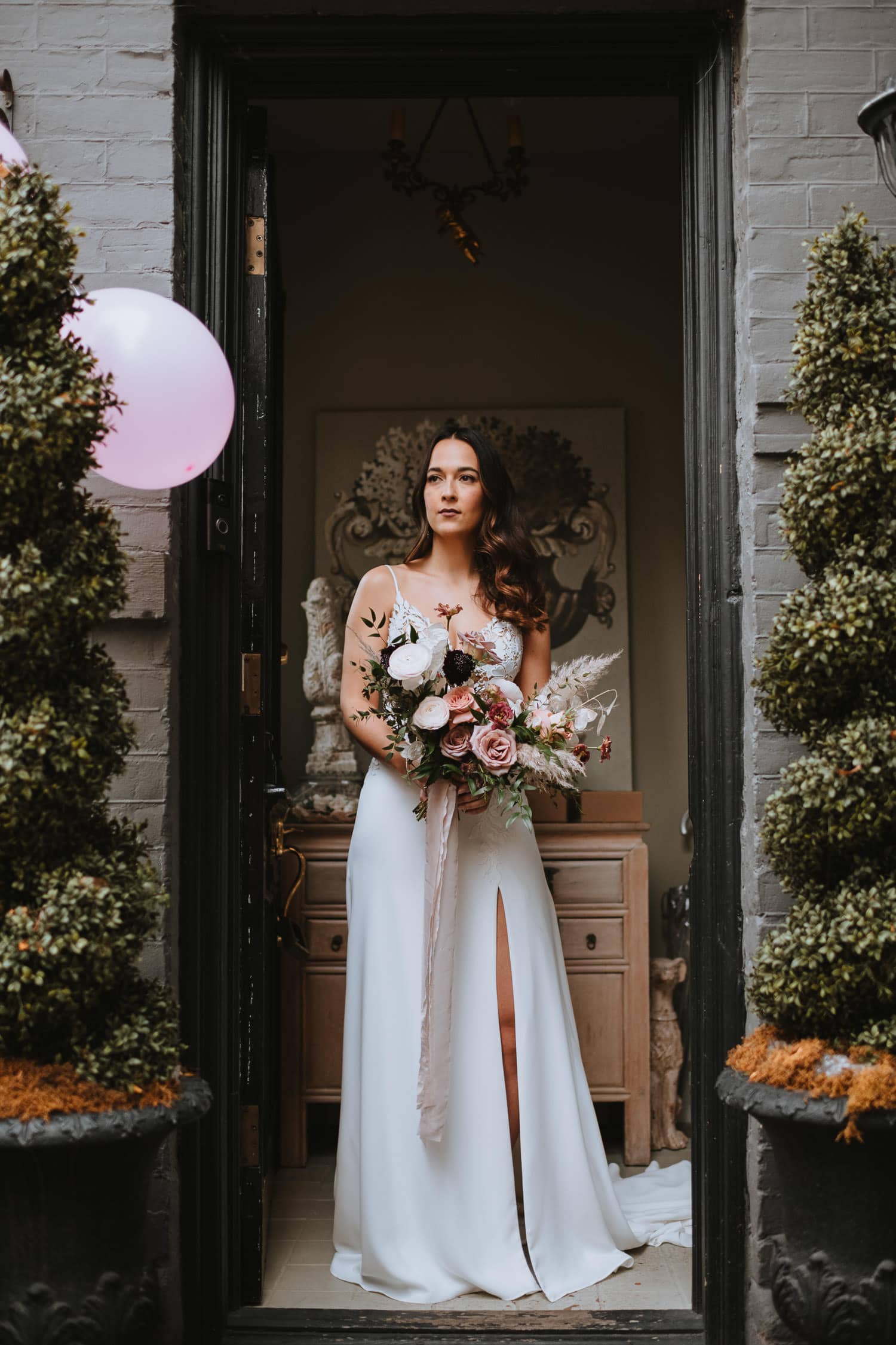 bridal portrait surrounded by pines and dark grey brick wall
